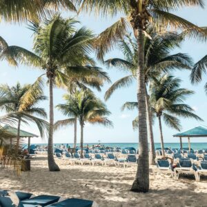 Sunny beach in Nassau with palm trees, sunbeds, and golden sand inviting relaxation in tropical paradise.