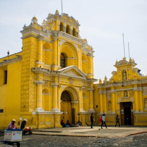 A vibrant yellow church in Guatemala City with local people and architecture.